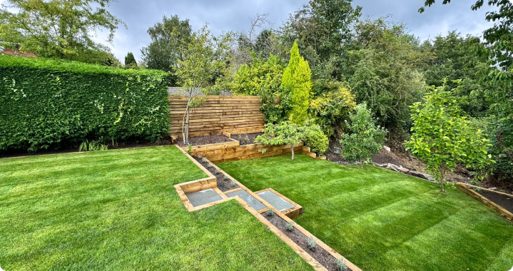 A landscaped lawn with stone steps, timber raised beds and mature planting