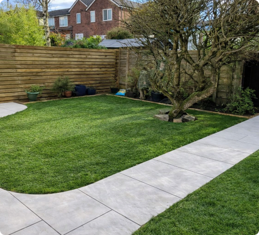 A finished garden with a curved lawn, stone patio and timber fencing