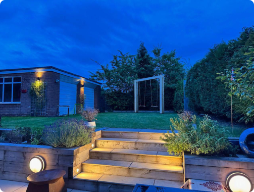 Garden lighting illuminating timber steps and raised beds at dusk